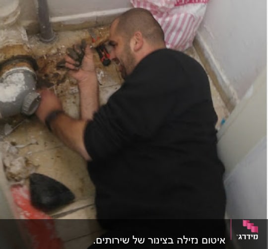 אדם עובד על צינור עם כלי עבודה